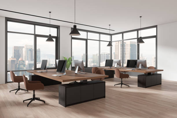 istock Stylish coworking interior with pc computers on desks in row, panoramic window 2156735764