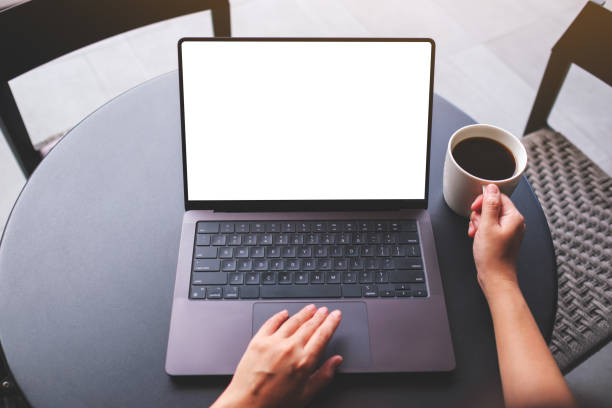 istock Top view mockup image of a woman working on laptop computer with blank white desktop screen while drinking coffee in cafe 2156741109