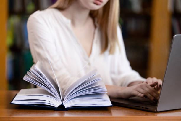 istock a girl sits at a table in a library, reading a book and taking notes. 2156742401