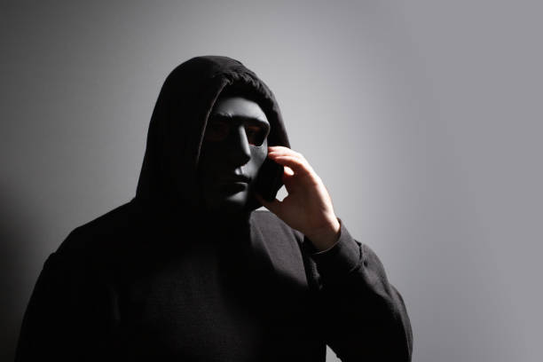 istock Phone Scammers, man in a mask with a phone, criminal network stealing data, hacker breaking into accounts, online safety compromised. 2156742666