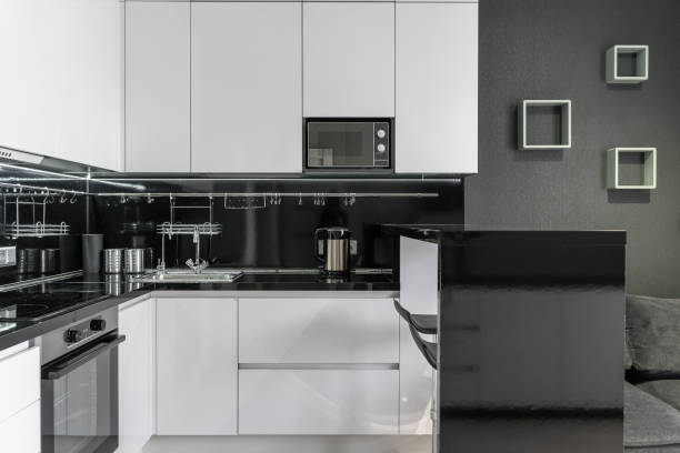 istock modern minimalist black and white kitchen.  Kitchen with built-in kitchen appliances, microwave, oven, refrigerator. The countertop and dining area in the kitchen are made of black stone. 2156748623