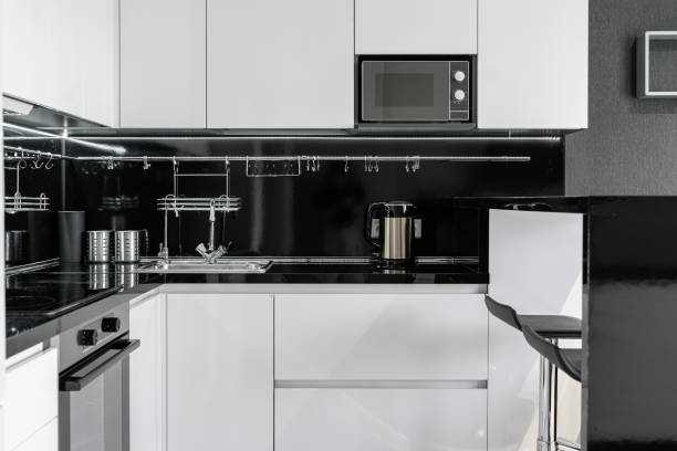 istock modern minimalist black and white kitchen.  Kitchen with built-in kitchen appliances, microwave, oven, refrigerator. The countertop and dining area in the kitchen are made of black stone. 2156748636