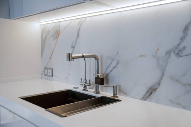 istock Stainless steel faucet on white marble countertop 2156756639