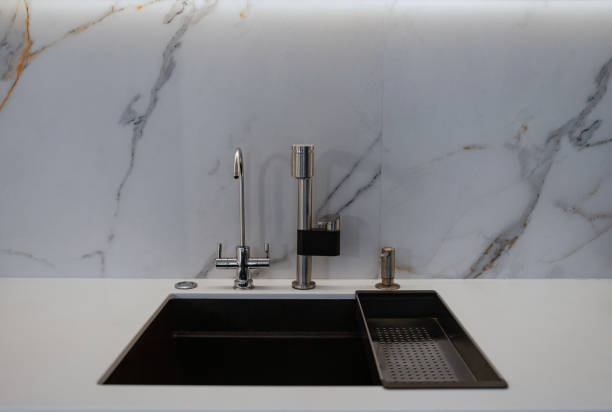 istock Kitchen sink and stainless steel faucet in a marble kitchen 2156756640