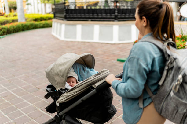 istock Mother walking with a baby carriage at town square 2156757593
