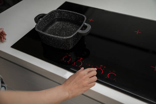 istock Female hand press button on control panel of electric cooker hob with pot 2156765038