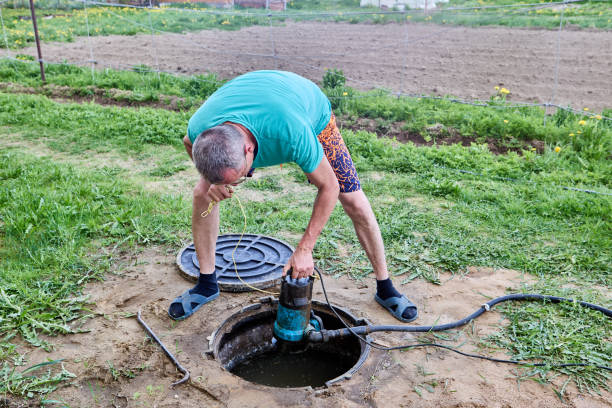 istock Worker pumping sewage waste from septic tank with wastewater pump through maintenance hole. 2156767785