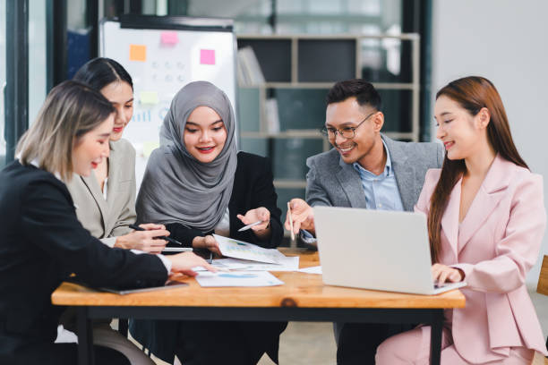 istock Diverse business team analyzing data and discussing strategies during an office meeting, using documents and a laptop. 2156771672