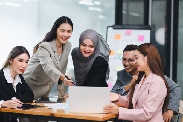 istock Diverse business team analyzing data and discussing strategies during an office meeting, using documents and a laptop. 2156771688