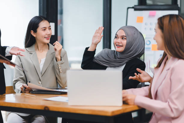 istock Cheerful business team actively engaging and sharing ideas during an office meeting, using documents and a laptop. 2156771689