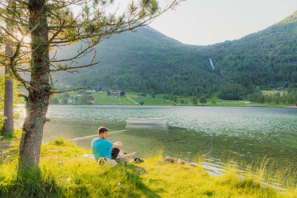 istock Man With Dog Contemplating Sunset Over Scenic Lake With Waterfall View 2156776485