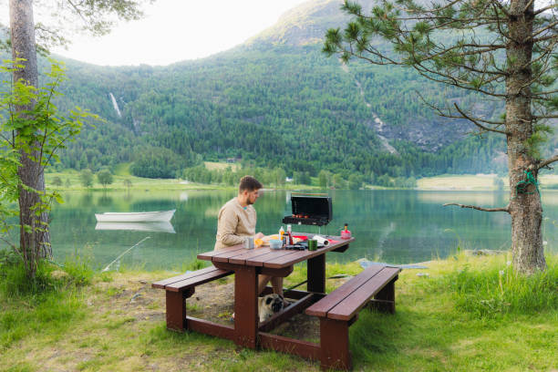 istock Man Grilling Sausages With Scenic Lake View 2156776740