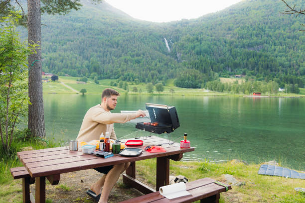istock Man Grilling Sausages With Scenic Lake View 2156777382