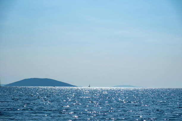 Ripple sea joins with blue sky background texture. Empty clear sparkle sea water surface, ocean indigo color, summer vacation. Copy space
