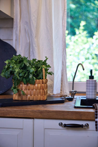 istock White kitchen interior with wooden worktop, black sink and tap under the window 2156781117