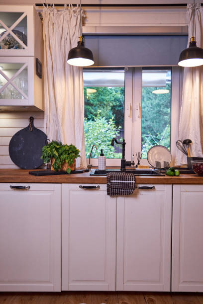 istock White kitchen interior with wooden worktop, black sink and tap under the window 2156781461
