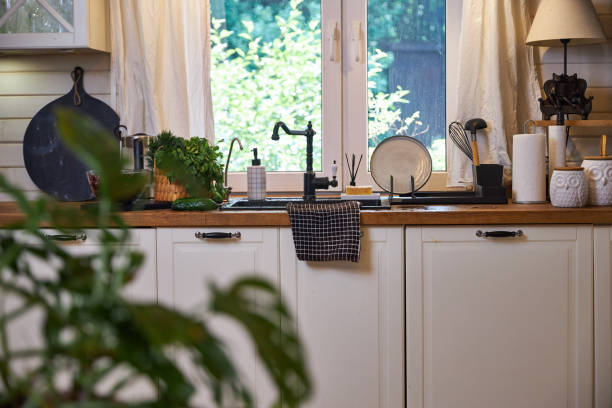 istock White kitchen interior with wooden worktop, black sink and tap under the window 2156781644