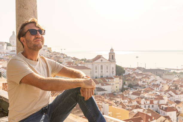 istock Man Sitting on Traditional Terrace Overlooking Lisbon's Alfama District 2156783157