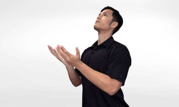 istock Young Asian Man Praying With Hands Upturned and Eyes Looking Upwards 2156785603