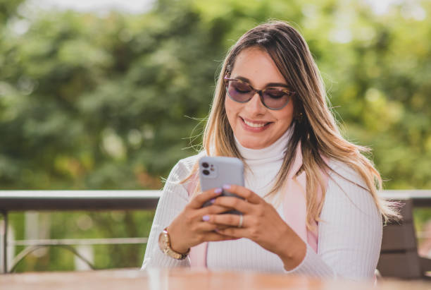 istock young latina woman using her cell phone and smiling 2156792167