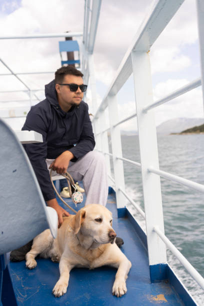 istock Young man with his dog on a ferry boat 2156796043