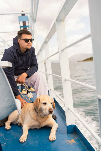 istock Young man with his dog on a ferry boat 2156796050