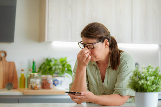 Tired woman suffering eyestrain using phone. Massaging her nose