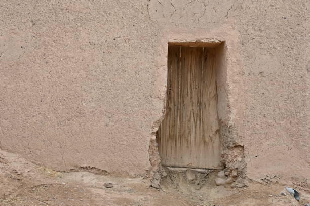 Old abandoned house with a weathered facade and peeled off to the stone base. Opened wooden door. Lanzarote, Canary Islands, Spain.