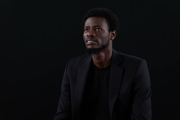Thoughtful businessman. Young man focusing on work. Black background.