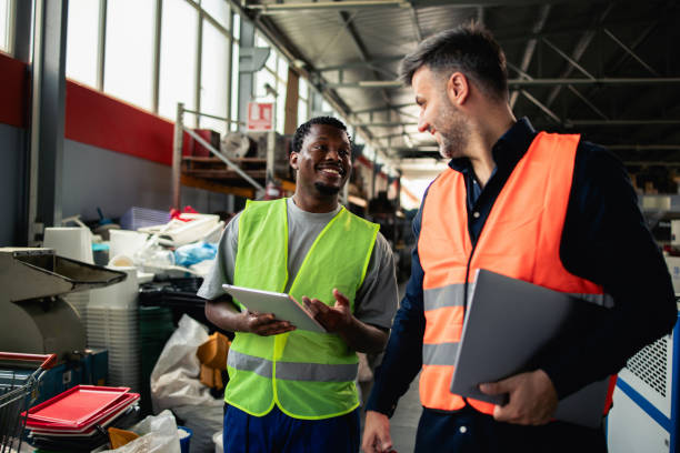 Two factory colleagues discussing the production strategy Two workers at the PVC production factory cooperating and checking the quality of production together working class stock pictures, royalty-free photos & images