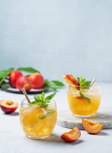 istock Two glasses with peach cocktail, lemonade or iced tea on a light background. 2156801014