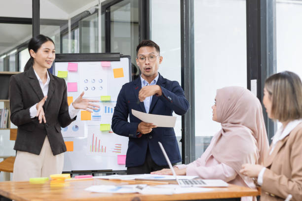 istock Group of asian business people working and brainstorming in workshop and analyzing marketing reports startup project infographics in the office. 2156802411