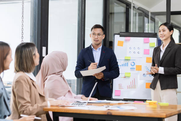 istock Group of asian business people working and brainstorming in workshop and analyzing marketing reports startup project infographics in the office. 2156802415