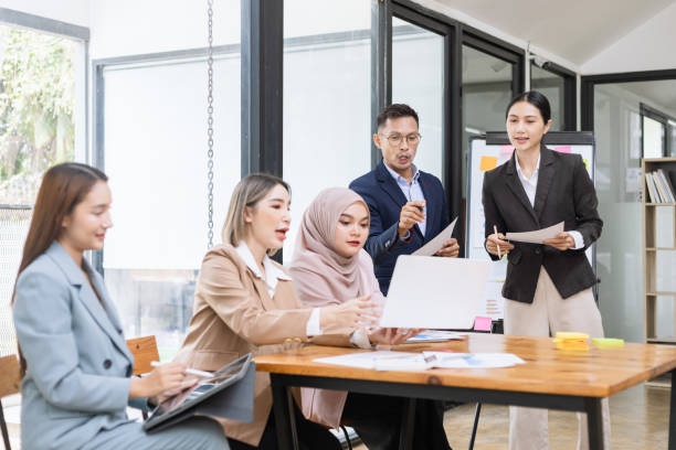 istock Group of asian business people working and brainstorming in workshop and analyzing marketing reports startup project infographics in the office. 2156802425