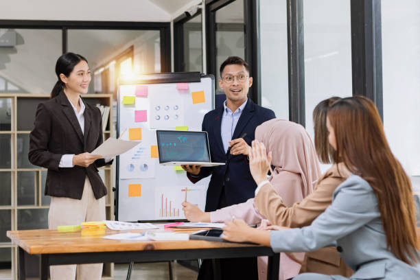 istock Group of asian business people working and brainstorming in workshop and analyzing marketing reports startup project infographics in the office. 2156802438