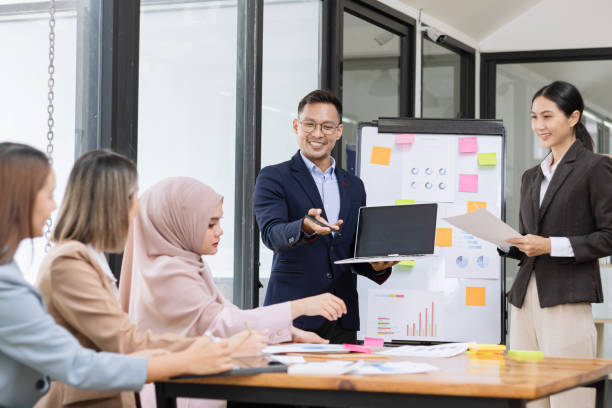 istock Group of asian business people working and brainstorming in workshop and analyzing marketing reports startup project infographics in the office. 2156802440
