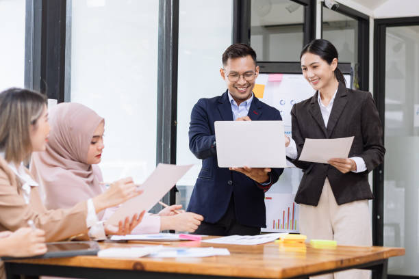 istock Group of asian business people working and brainstorming in workshop and analyzing marketing reports startup project infographics in the office. 2156802447