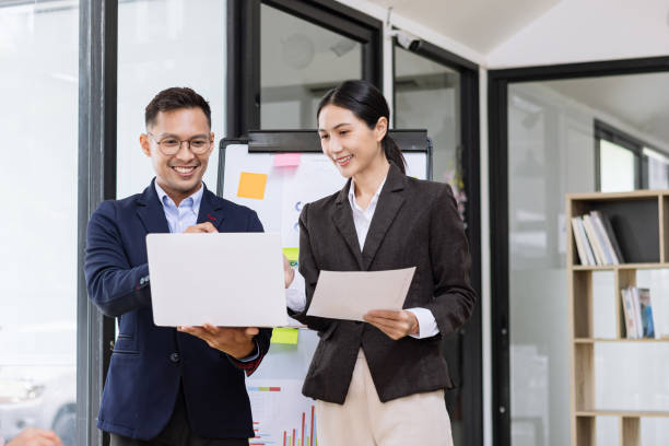 istock Asian coworkers standing up and looking document paper  together in office. 2156802448