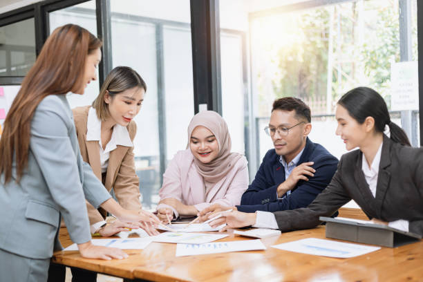 istock Group of asian business people working and brainstorming in workshop and analyzing marketing reports startup project infographics in the office. 2156802450