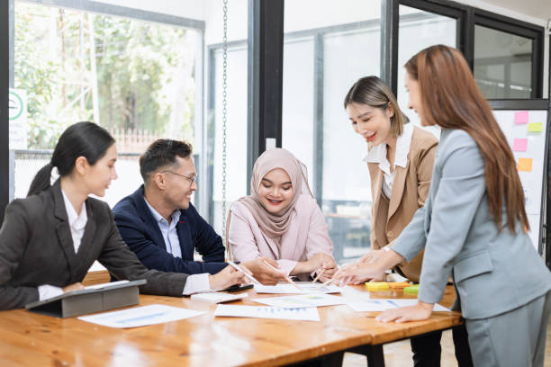 istock Group of asian business people working and brainstorming in workshop and analyzing marketing reports startup project infographics in the office. 2156802457
