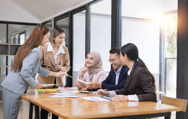 istock Group of asian business people working and brainstorming in workshop and analyzing marketing reports startup project infographics in the office. 2156802491