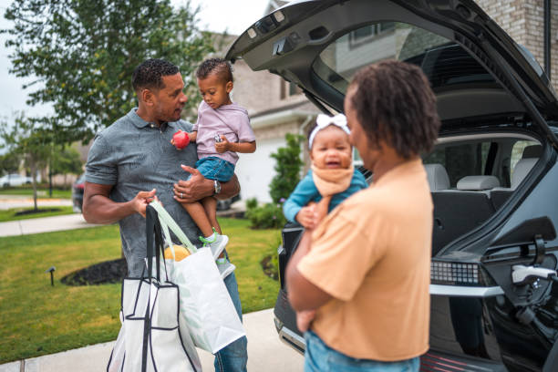 istock Diverse Family Unloading Groceries by Eco-Friendly Home and Car 2156804473