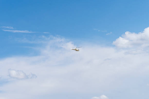 On a summer day a firefighting helicopter flies over the blue sky. Non-passenger manned aircraft on surveillance duty.