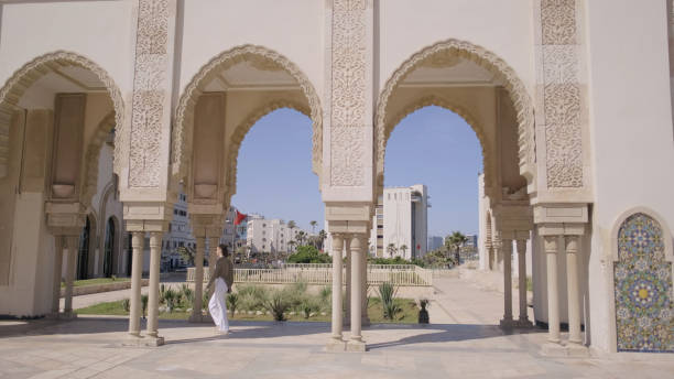 Young woman walks under stone archway on streets of old village