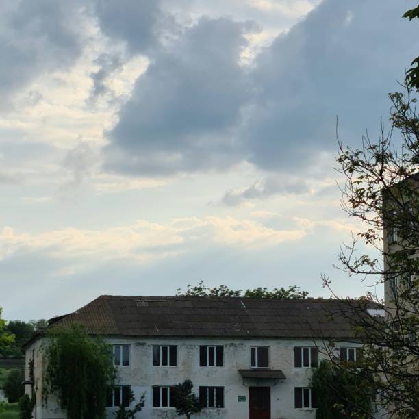 A house with trees and clouds in the sky. Sky. Outdoor. Tree. House