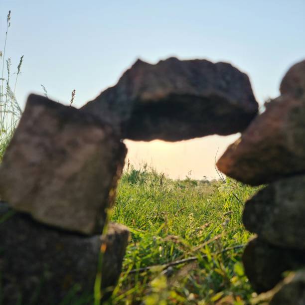 A person standing on a rock. Outdoor. Rock. Mountain. Sky. Grass