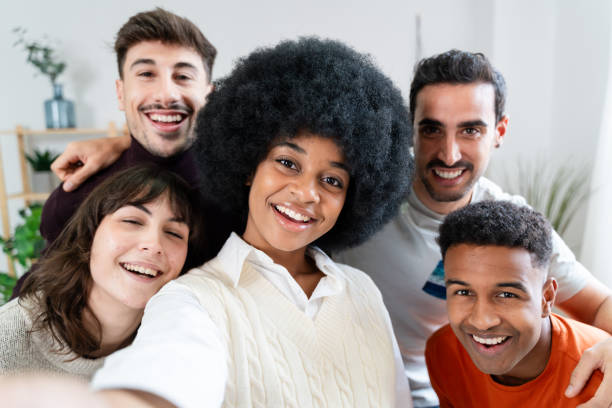 istock A group of diverse friends take a selfie together while smiling happily inside a home 2156817733