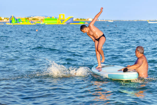 istock Caucasian father with sons playing in the sea while jumping from a standup paddleboard 2156818797