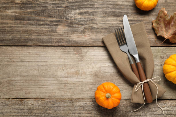 istock Cutlery, napkin and pumpkins on wooden background, flat lay with space for text. Table setting 2156819892