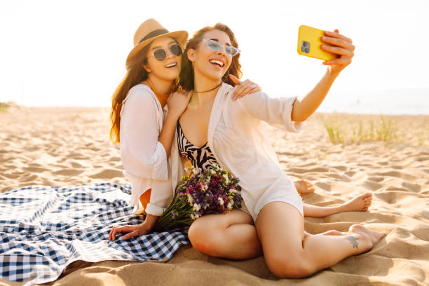 istock Stylish pretty women on summer vacation on beach  taking selfie. 2156820964